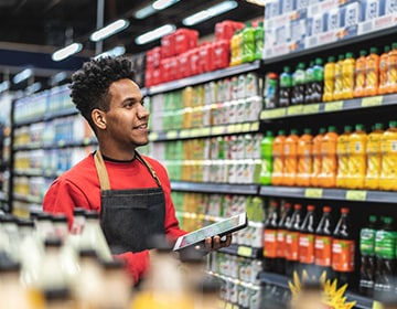 young man working at the grocery store using a mobile device to scan inventory