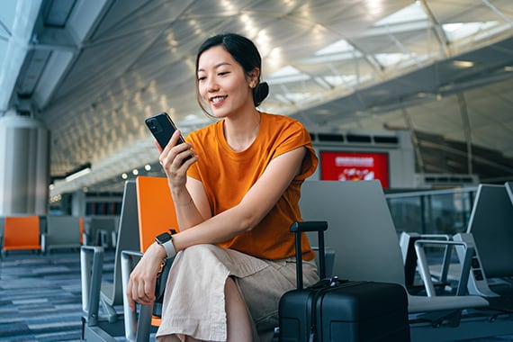 Barracuda showcase image of woman in airport using cloud technology from smartphone.