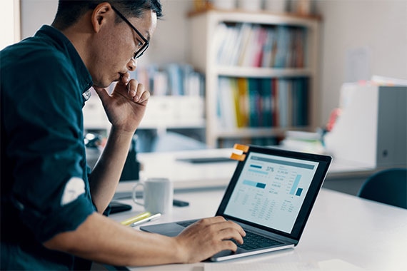 Person using laptop displaying dashboard with charts at office desk