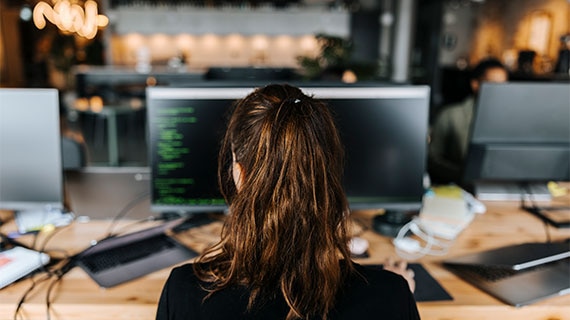 Software engineer working at a multi-monitor workstation, developing a ContractIQ workflow with selective parallel approval logic, automated routing, and enterprise process orchestration.