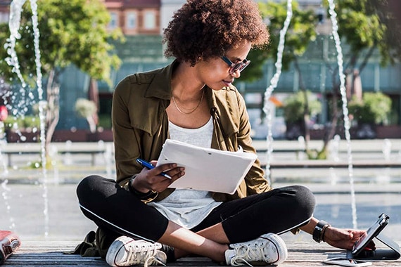 woman is working remotely on tablet in a park outside