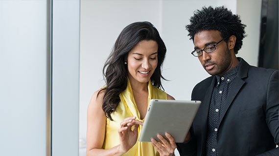 Consultants reviewing a tablet together during a cybersecurity and compliance assessment aligned to NIST and PCI frameworks.