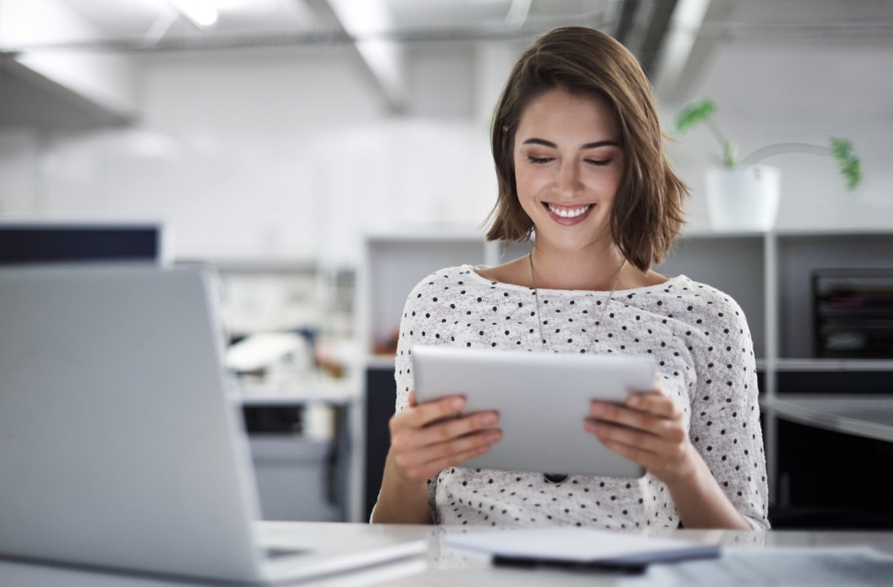 Girl sitting in front of an ipad with a smiling expression.