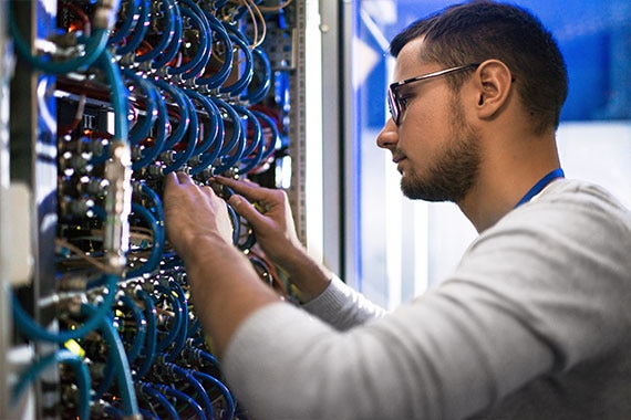 IT engineer configuring network cables in a data center to optimize cloud infrastructure.