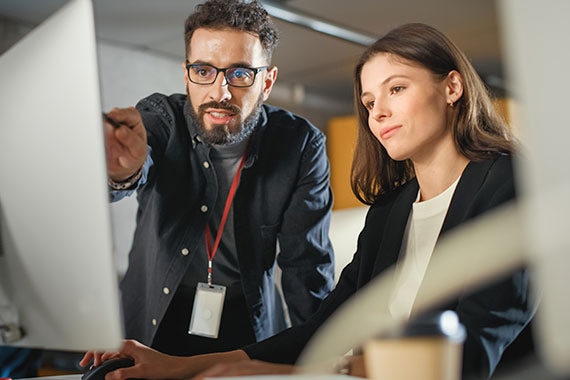 Instructor guiding a student through hands-on computer training, demonstrating tools and practical exercises for real-world learning.