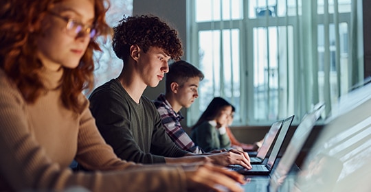 thumbnail image of college students working on laptops in a classroom environment