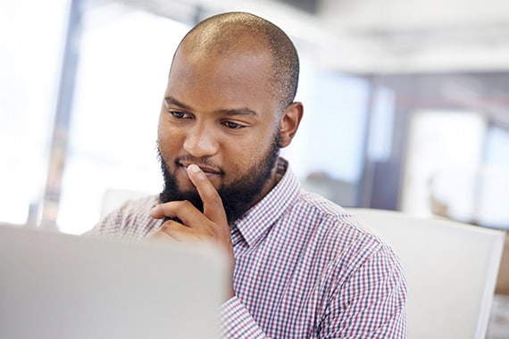 Man thinking while sitting at office laptop computer