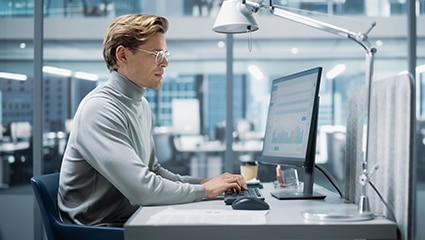 Person using desktop computer in bright office.
