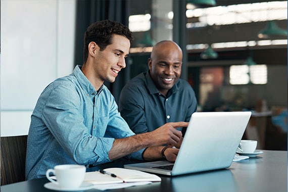 Two colleagues reviewing content together on a laptop at a table