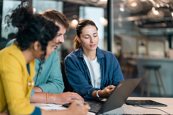 thumbnail image of employees working on a shared laptop in an office environment
