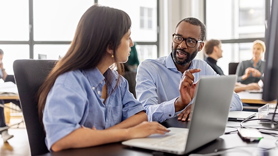 Coworkers in a office at a laptop.