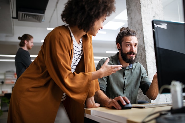 employees collaborating in front of a computer in an office setting