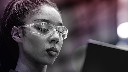 image of a worker wearing protective eyewear reviewing information on a computer monitor