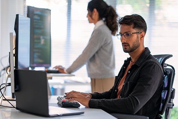 Man working on laptop computer in IT workspace.