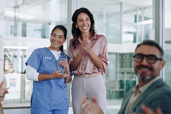 female nurse accepting an award in front of healthcare professionals clapping 