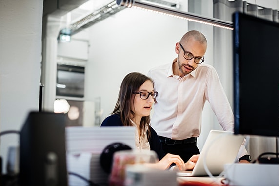 Image of a man and woman looking at a laptop in an office