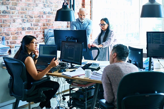 Engineering team collaborating in a modern office to analyze workload data, identify underutilization, and optimize storage policies.