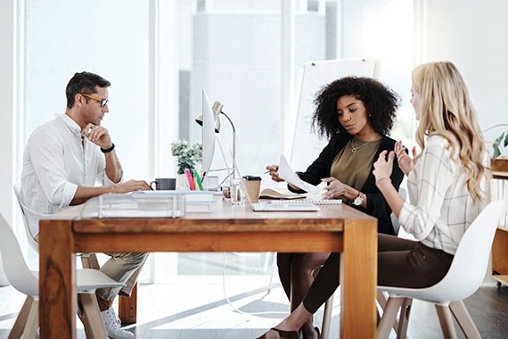 Three business professionals collaborating in a modern office on cloud cost optimization strategies to unlock savings and maximize ROI.