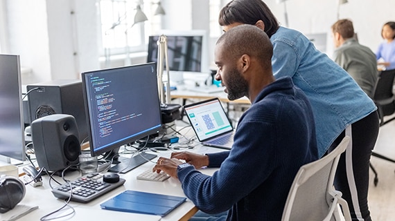 Two coworkers collaborating on code in bright office.
