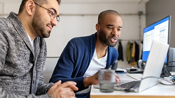 Two coworkers collaborating on code in bright office.