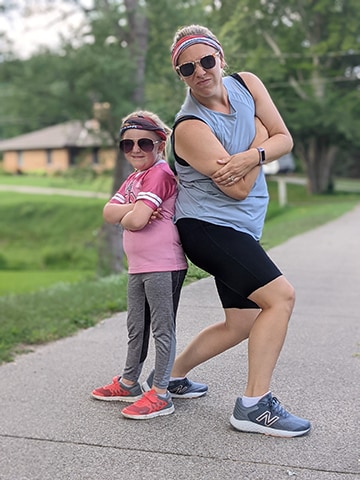 dult and child pose back-to-back for a photo in athletic gear and matching headbands