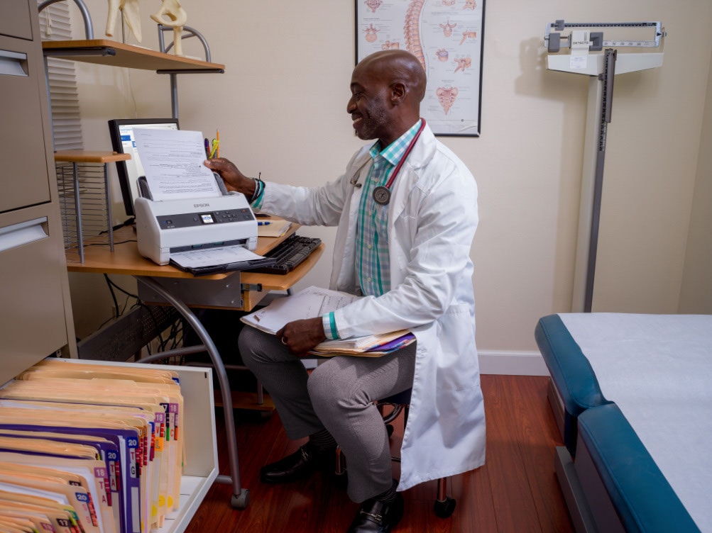 A doctor scanning a document using an epson scanner/printer.