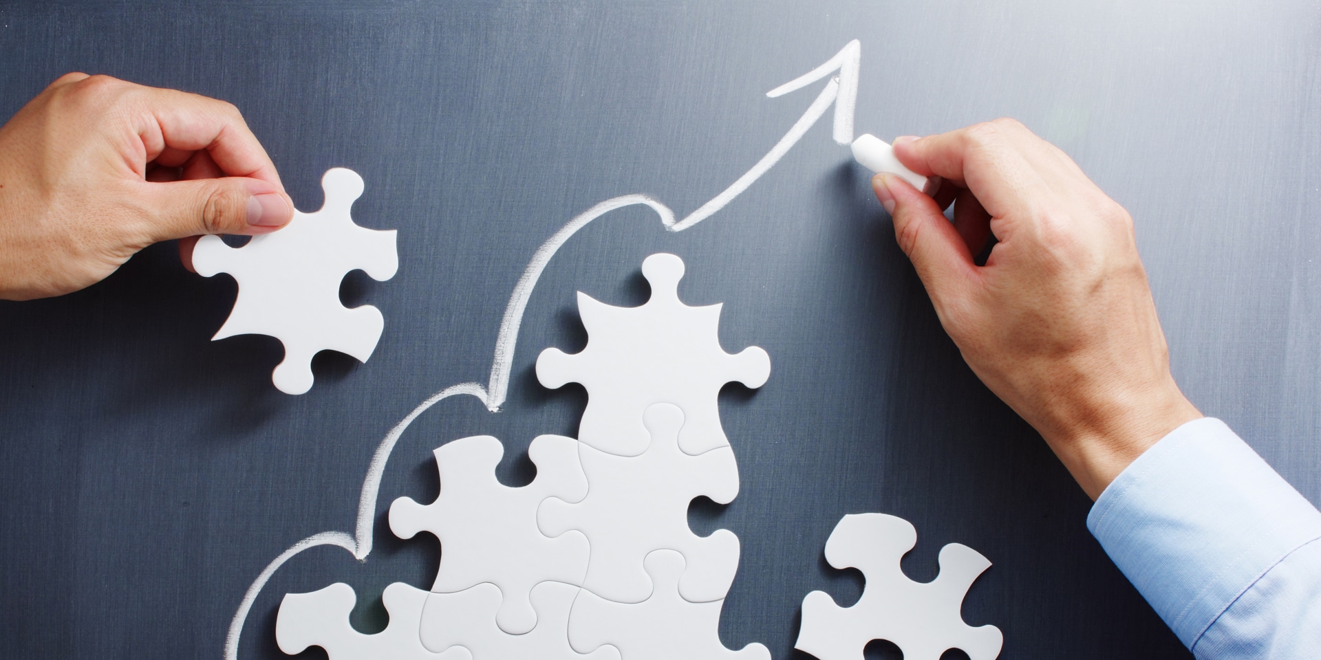 Man holding a puzzle piece and making a line with a piece of chalk