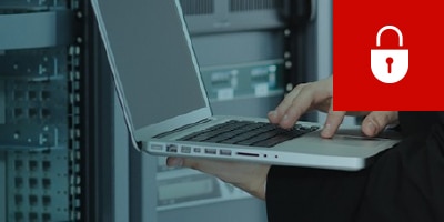 Person in server room, working on notebook computer