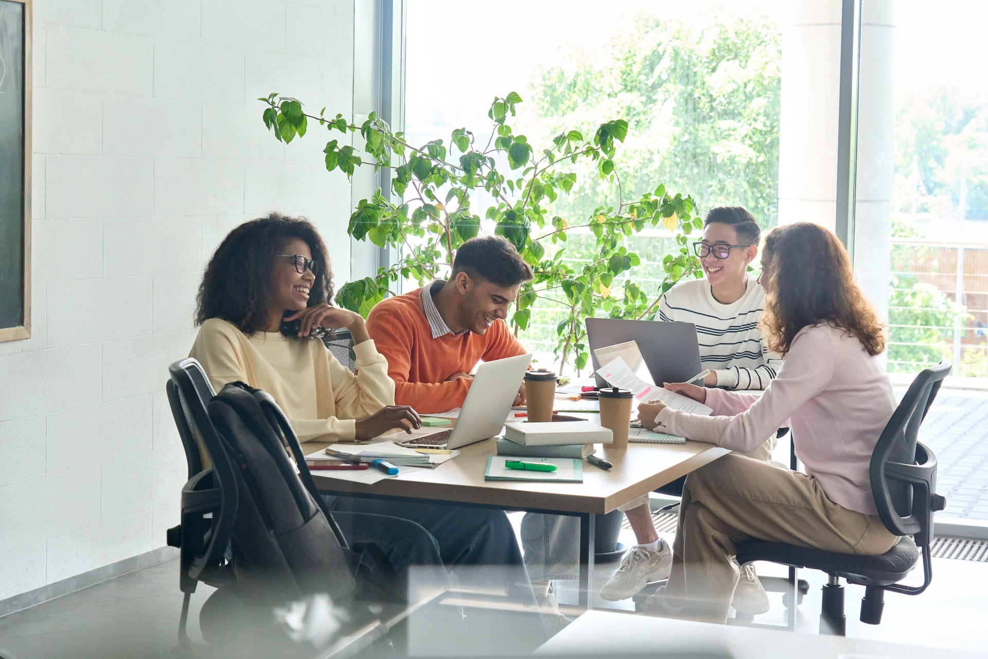 People sitting on a table working and laughing in an office meeting room.