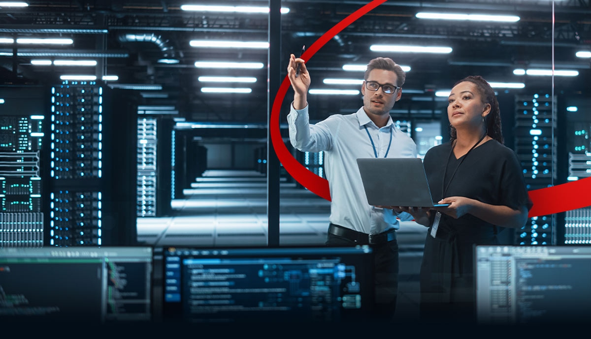 Two IT professionals in a modern data center reviewing AI infrastructure on a laptop.