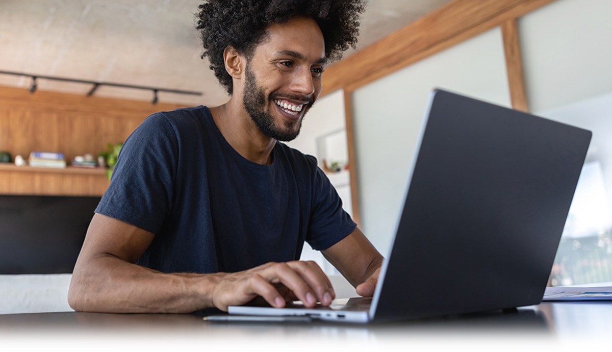 Smiling individual using an AI PC laptop computer.