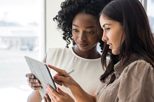 women looking at device with serious expression