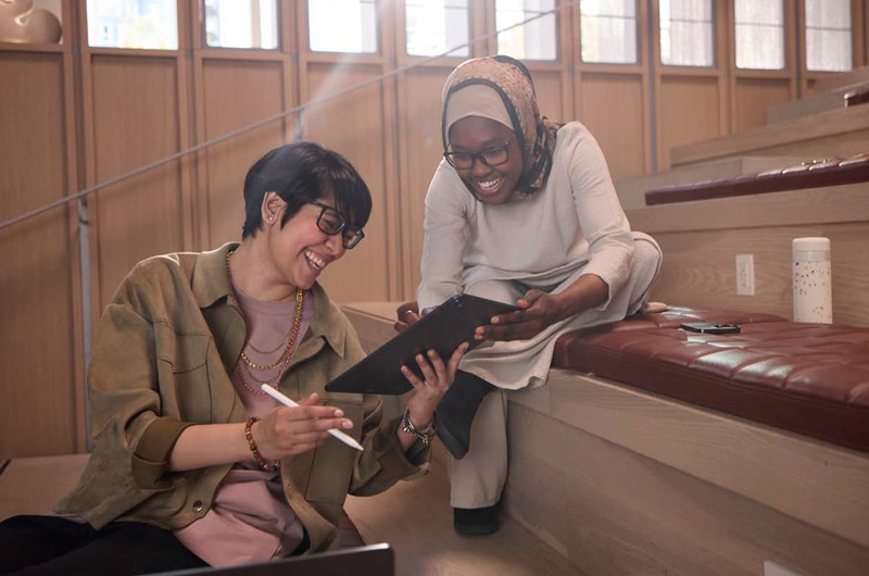 image of two happy coworkers reviewing information on an Apple iPad tablet