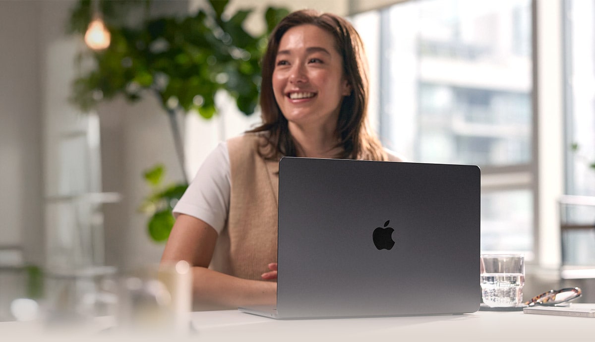 Happy woman sitting with Apple MacBook