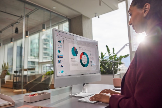 Woman working on charts and data on an Apple Studio Display.