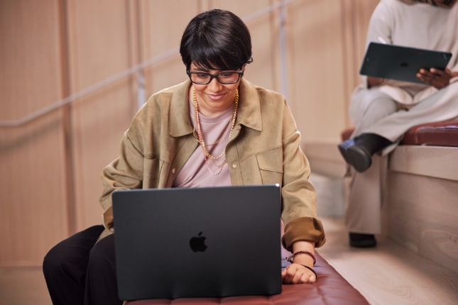 Woman working on a MacBook Pro in a public area.