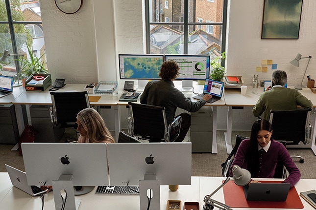 lifestyle image of a group of employees working on Apple computers in a shared office environment