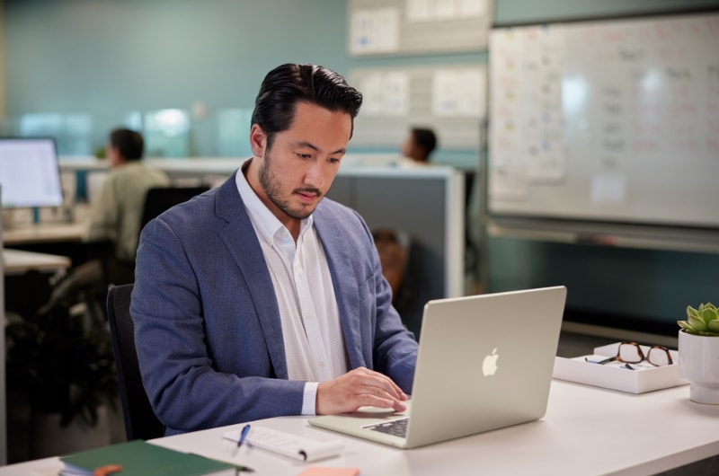 A finance worker working on a MacBook in an office.