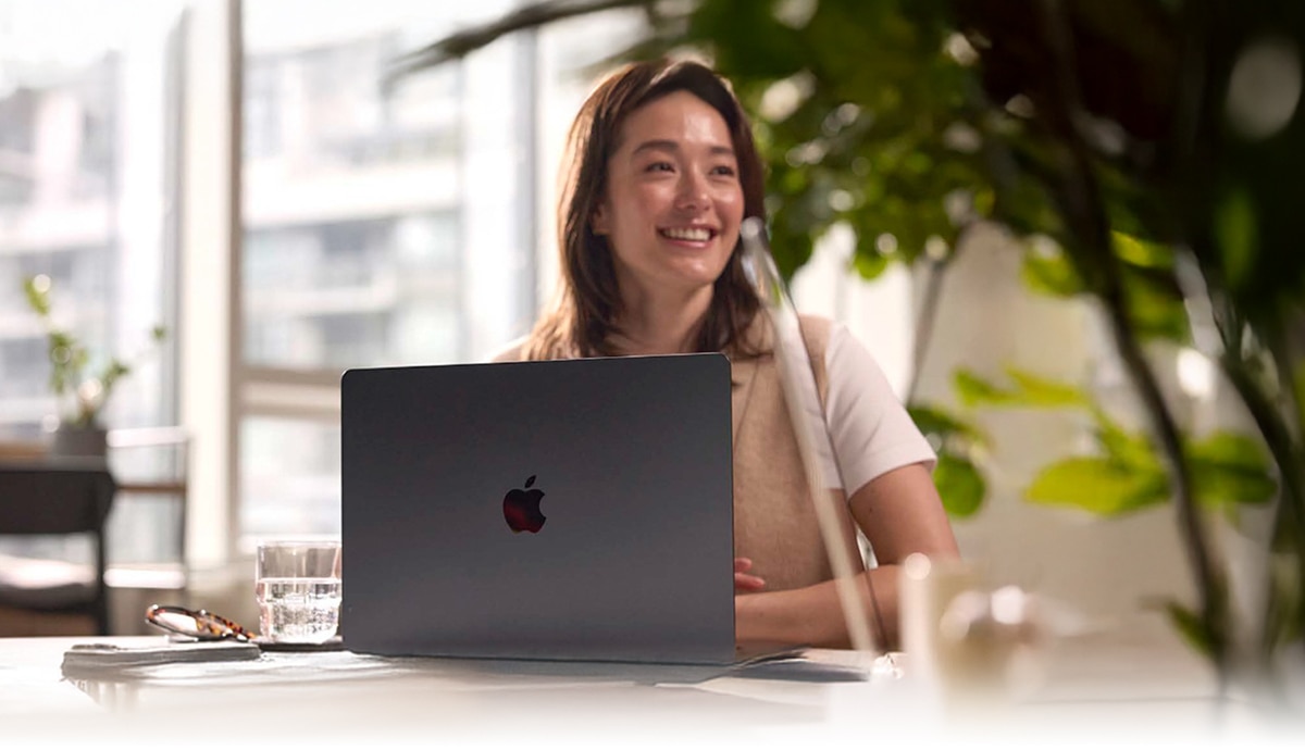 image of a woman working at a desk on an Apple MacBook computer
