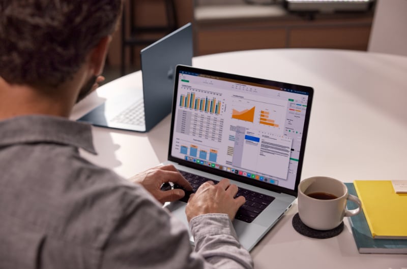 Man working on financial data with a MacBook.