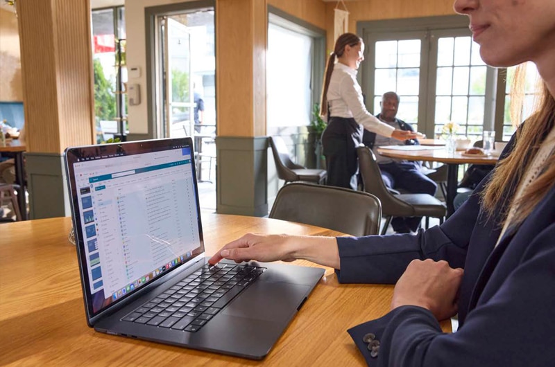 image of a woman working on an Apple MacBook computer inside a cafe