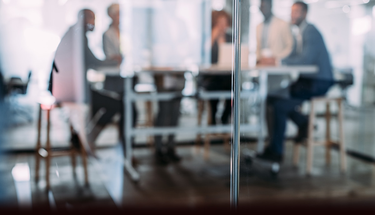 Out-of-focus office environment with employees in a conference room.