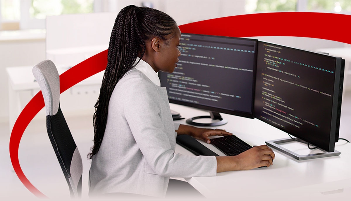 Professional woman working on dual monitors with AI programming code, symbolizing artificial intelligence solutions powered by Intel and CDW to accelerate enterprise workloads.
