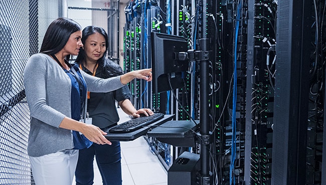 IT engineers manage servers in a data center, supporting centrally managed hybrid cloud operations across cloud, datacenter, and edge.