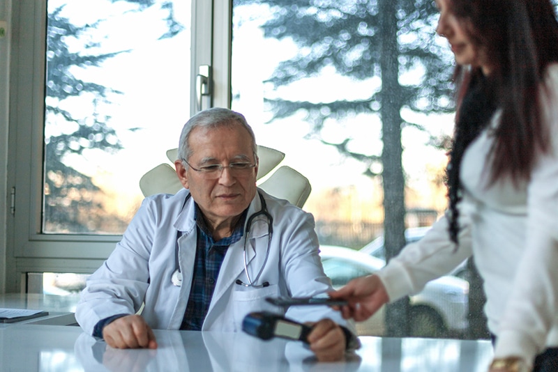 image of a doctor using RFID technology to scan a patient's smartphone.