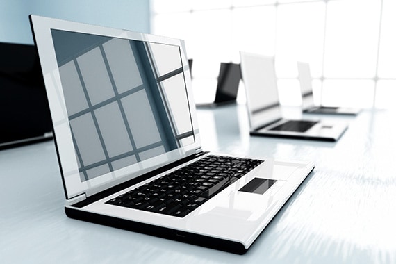 row of laptops on desk in office