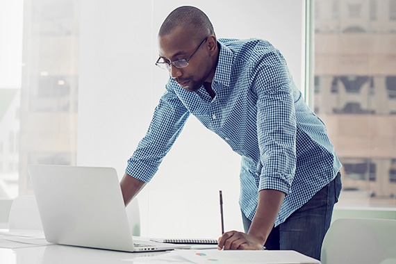 man looking down at work laptop in office