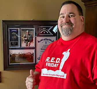 A man with his thumb up wearing a R.E.D. Friday shirt 