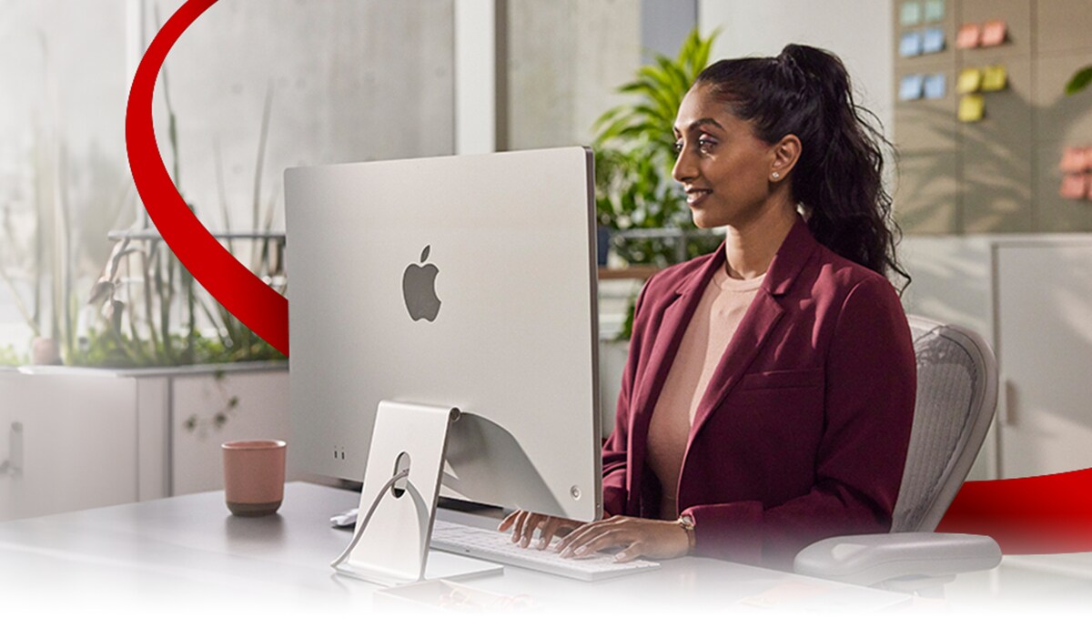 Woman working in front of an Apple desktop computer.
