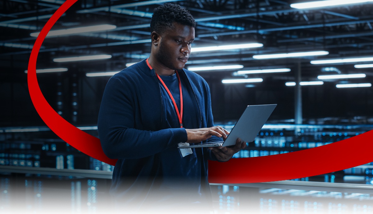 hero image of an IT specialist working on a laptop in a data center.